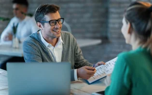 happy-businessman-talking-his-colleague-while-going-through-financial-reports-office
