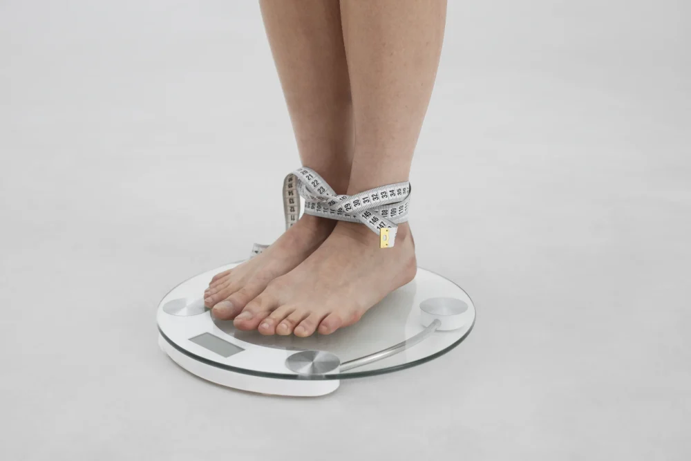 young-woman-with-eating-disorder-using-tape-measure